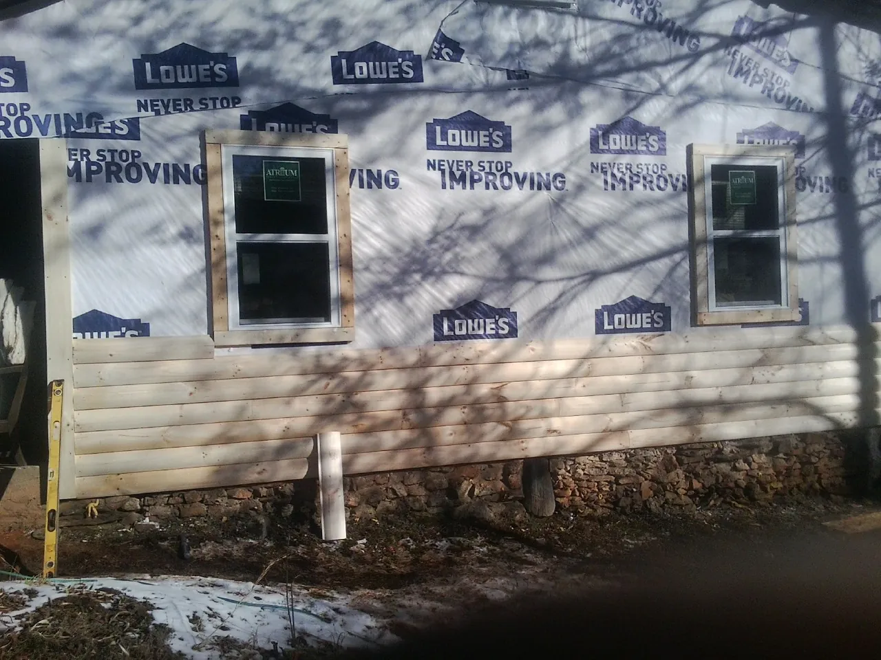 House wrap and new log siding going up on an exterior wall in Ely