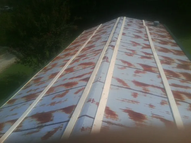 Rusted metal roof panels with new wood purlins before replacement — Storm Damage Roof Repair in Ely by Roofing Brothers