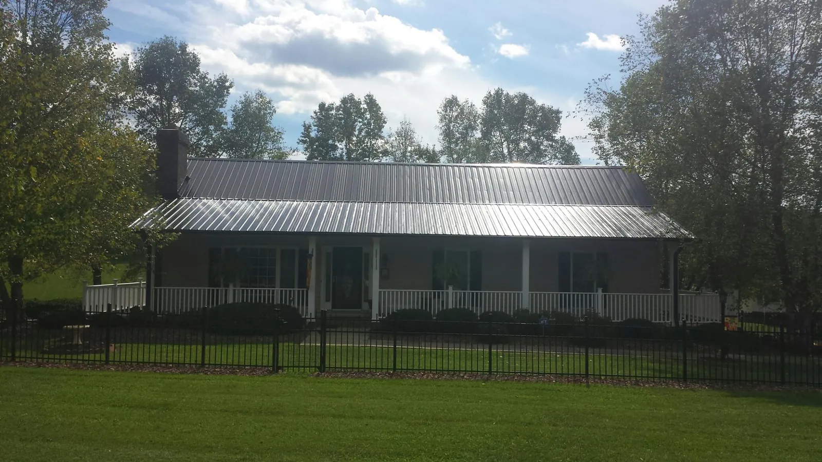 Gray metal roof on a brick ranch with a full width front porch — Gutter Guard Installation work by our crew in Ely